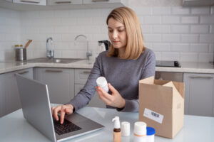 A woman in the kitchen with a laptop ordering a dietary supplement online.