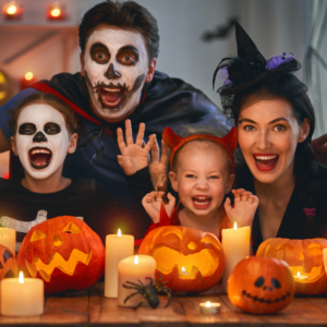 A family in Halloween costumes with pumpkins and candles