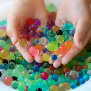 A person holding a bunch of water beads in their hands.