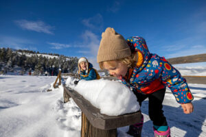 Two young children playing outside and licking snow 