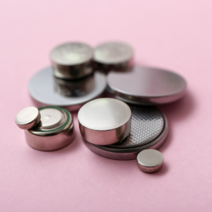 Image of a bunch of button batteries of all sizes on a pink background