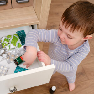 A toddler opens a cabinet drawer and has access to a variety of different medicines.