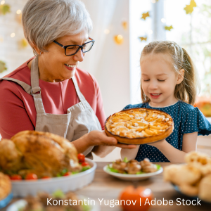 A young child and her grandmother are holding a Thanksgiving Day pie.