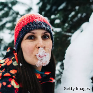 A person dressed in warm winter clothes with snow on their lips.