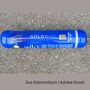 A nitrous oxide canister named Gold Whip lying on the ground.