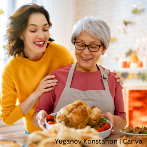A young woman and her mother smile while placing the Thanksgiving turkey on the table for dinner.