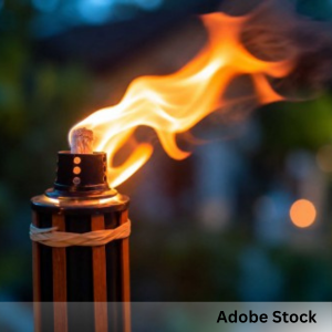 Close-up of a lit tiki torch flame outdoors at dusk.