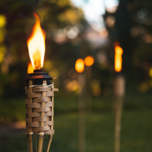Lit tiki torches lining an outdoor path at dusk.